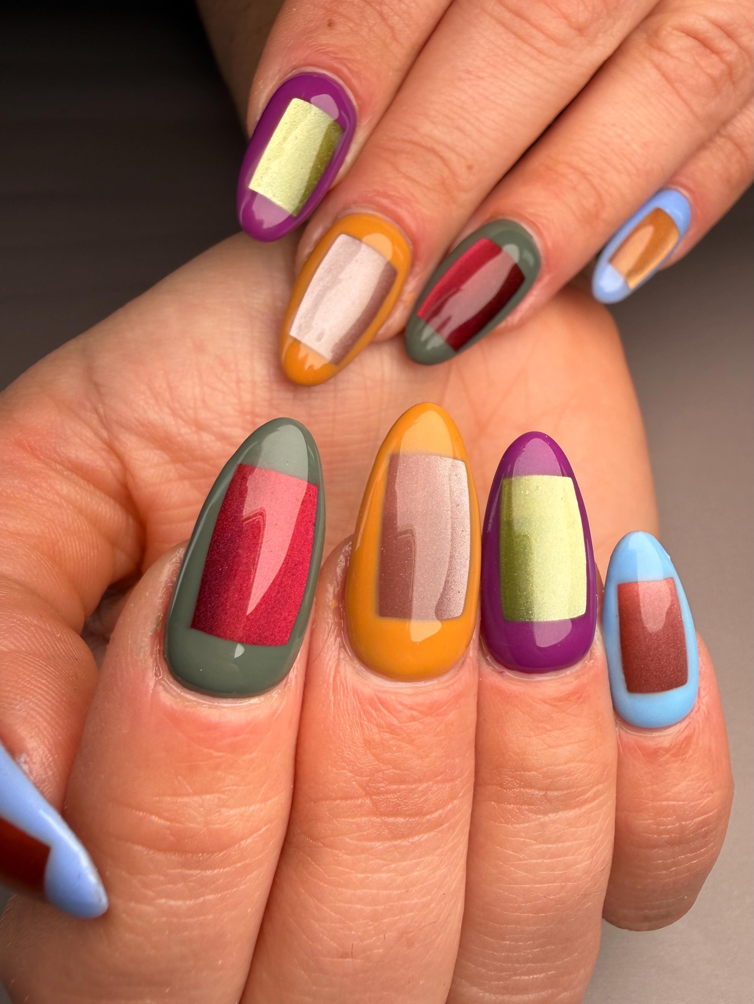 Two hands with long nails in a colour-block frame design, purple, orange, green and blue edges around contrasting centres